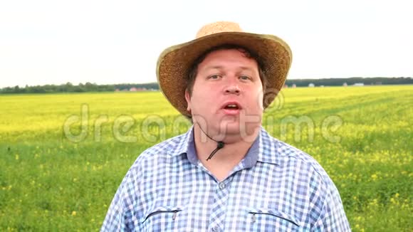 快乐的农夫站在田野里眨眼微笑在阳光明媚的日子戴牛仔帽视频的预览图