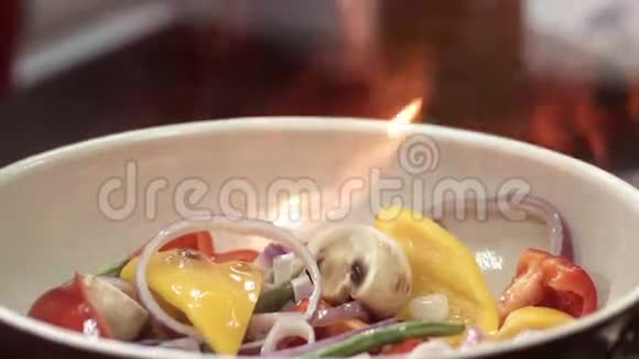 红辣椒蘑菇和紫色洋葱在陶瓷煎锅中的火焰多汁蔬菜的特写视频的预览图