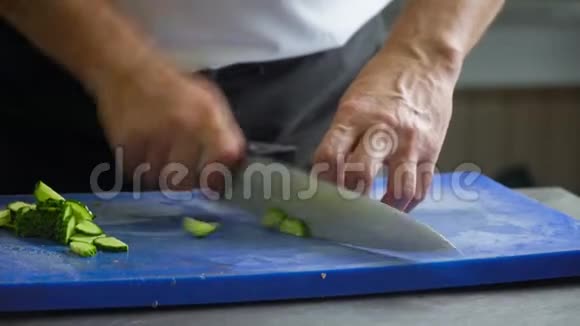 厨师把黄瓜切在蓝色的切割板上手的特写动作视频的预览图