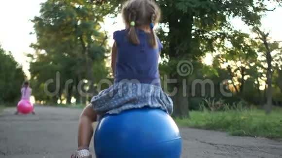 两个小女孩正穿着鲜艳的健身球在路上跳跃孩子们村里的游戏发展视频的预览图