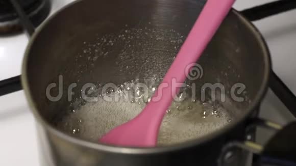 糖浆在炖锅里煮准备棉花糖可见的厚泡沫一个人把糖浆混合这样它就不会燃烧视频的预览图