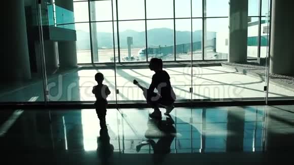 小男孩和他妈妈慢条斯理地看着机场的飞机视频的预览图