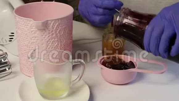 女人在量勺里混合不同的果酱准备棉花糖桌子旁边还有其他原料和视频的预览图