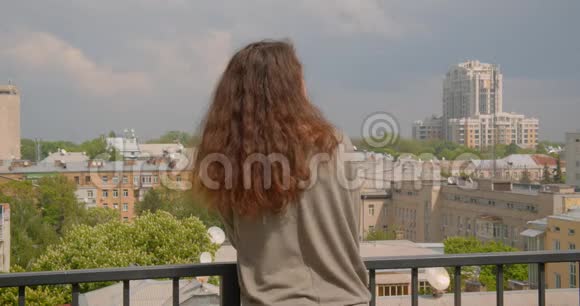 后拍摄的深色白种人模特在阳台上享受阳光的城市景观视频的预览图