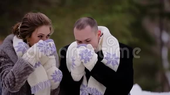 冬天两个情人坐在公园的长凳上喝热咖啡他们戴着相配的围巾和手套我们在杯子上视频的预览图
