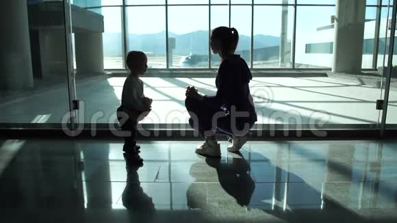 妈妈和小儿子透过机场的大窗户看飞机视频的预览图