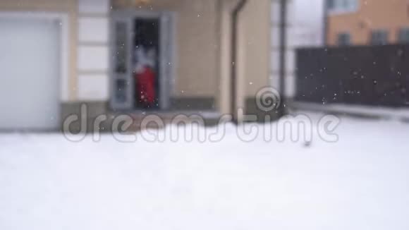 可爱的男人和女人跑出房子来到后院一个男人抓起雪扔向女孩她跑掉了视频的预览图