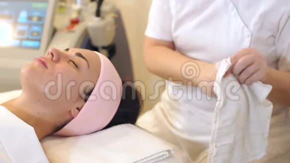 美容师用白餐巾纸在美容中心擦女孩的脸视频的预览图