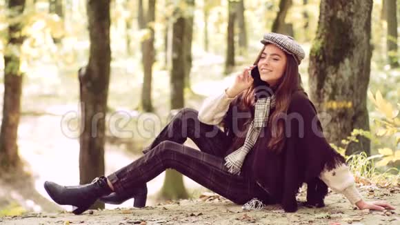 秋天的女人快乐的女人用智能手机社交媒体电话美丽的黑发少女坐在秋天的秋天视频的预览图