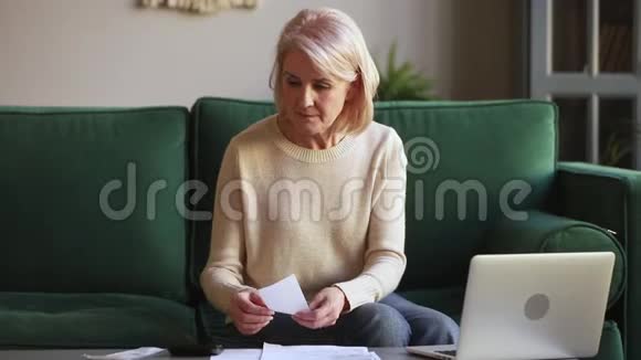严重的成熟女人会用手提电脑计算拿着文件的账单视频的预览图