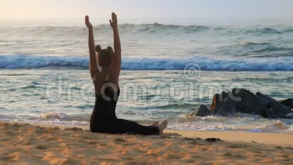 穿着黑色运动服的漂亮女孩坐在橙色海滩上视频的预览图