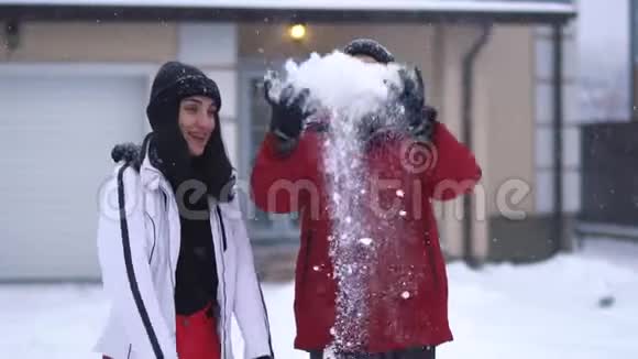 长胡子的男人把一把雪扔了起来女人站在附近举手快乐的夫妻在冬天的后院玩得开心视频的预览图