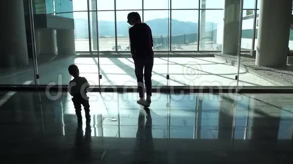 妈妈和小男孩到机场大厅的窗口看飞机视频的预览图