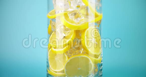 在一个大玻璃杯里放冰冷柠檬水在红色上拍摄特写慢镜头视频的预览图