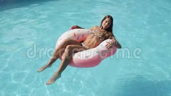 夏天少女坐在粉红色的充气戒指上漂浮在水上公园的水池上视频的预览图