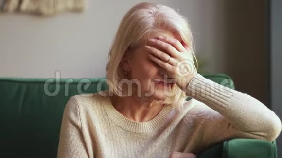 悲痛欲绝的老寡妇用手捂着脸哭泣视频的预览图