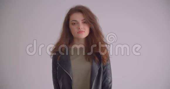 穿着皮夹克的漂亮黑发女孩看着镜头自信地孤立在白色背景上视频的预览图