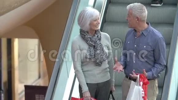 在购物中心乘坐自动扶梯的高级夫妻快乐视频的预览图