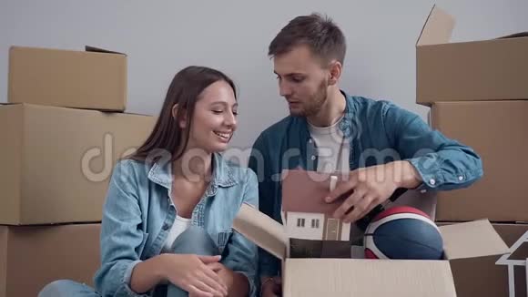 兴奋的年轻夫妇打开东西打开盒子在搬到新公寓时交谈视频的预览图