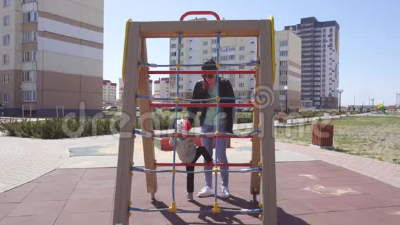 3岁的白种人小女孩和她的母亲在一个现代化的儿童游乐场玩耍运动器材视频的预览图