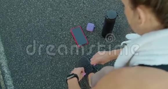 女跑步者的脚准备好用智能手表耳机和电话为音乐系鞋视频的预览图