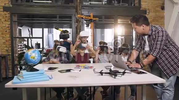 在计算机科学课上韩国教师带着带手提电脑和VR耳机的年轻学生视频的预览图