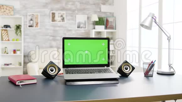 桌子上有绿色屏幕的现代笔记本电脑视频的预览图