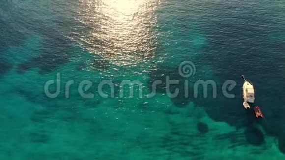空中俯视日落时阳光下爱琴海的青绿色海水海岸线停泊的船视频的预览图