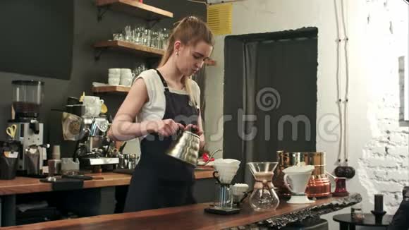 年轻的女咖啡师在时髦的现代咖啡馆咖啡店里把开水倒在咖啡场上倒在地上视频的预览图