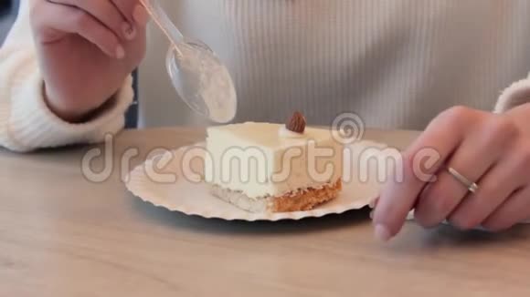 女人的手在咖啡馆里用白色毛衣的塑料勺子吃蛋糕视频的预览图