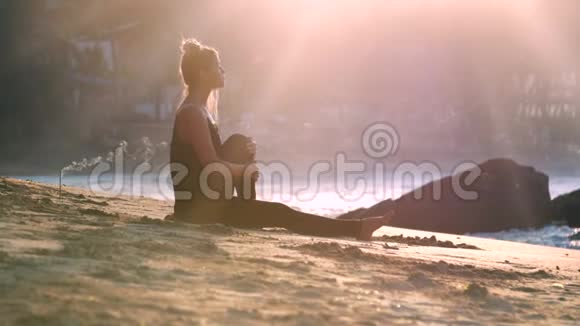清晨阳光照射下的女孩剪影坐在瑜伽位置视频的预览图