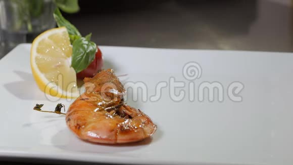 在餐厅煮大虾厨师把一片柠檬和一个樱桃番茄放在盘子里视频的预览图