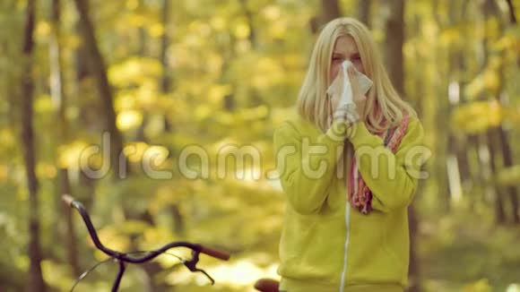 女人为秋天公园的普通感冒治病感冒季节流鼻涕向生病的女人打喷嚏视频的预览图