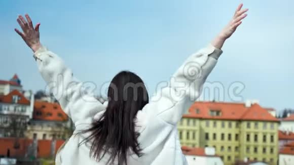 背景图片快乐的旅行女孩跳跃和挥动双手快乐的典型欧洲城市视频的预览图