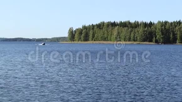 芬兰湖清澈的蓝色水松树和一艘船靠近视频的预览图