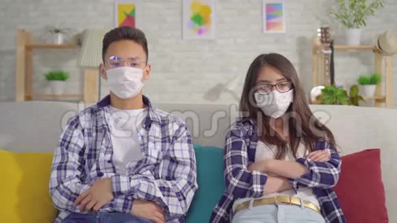 年轻的西安夫妇戴着防护口罩坐在沙发上视频的预览图
