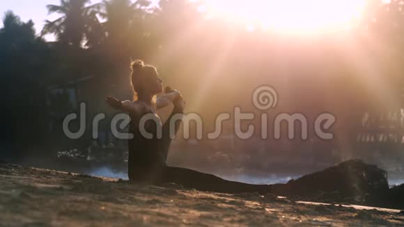 日出时美丽的女士在沙滩上做瑜伽视频的预览图