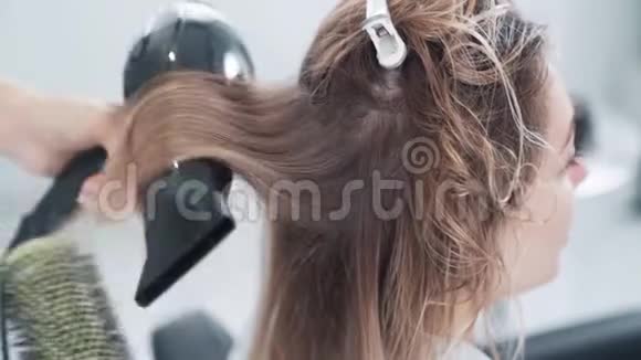 收拢理发师用圆梳擦干女人湿发慢动作视频的预览图