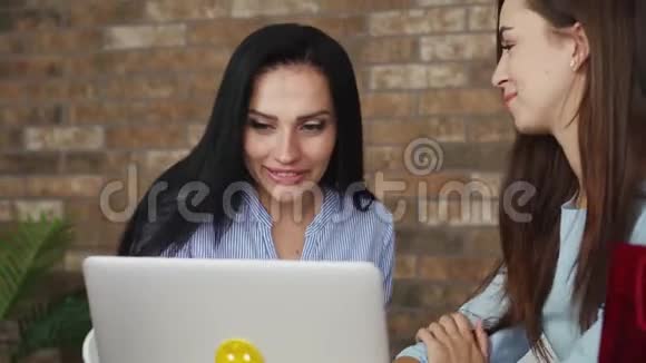 两个幸福的女人看着笔记本电脑屏幕活跃地说话视频的预览图