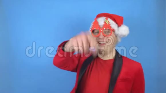穿着圣诞老人服装在蓝色背景下跳舞的白人年轻人新年及圣诞节概念视频的预览图