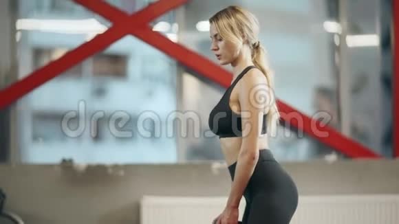 健身中心里蹲着哑铃的女运动员视频的预览图