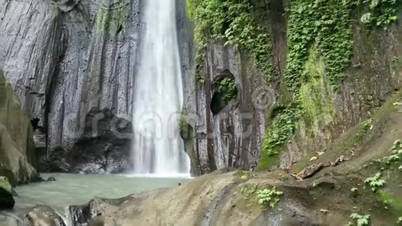在巴厘岛绿色热带雨林中观赏美丽的瀑布的女性的鸟瞰视频的预览图