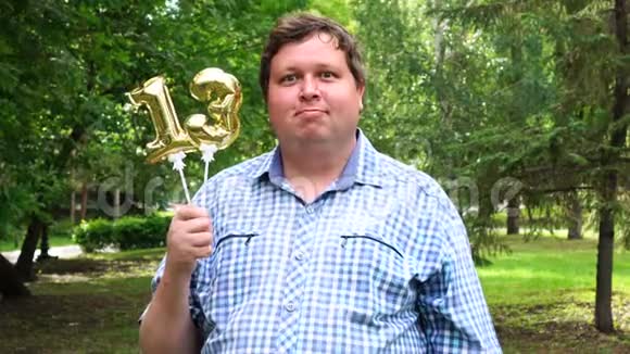 大个子拿着金色气球把13号放在户外13周年庆祝晚会视频的预览图