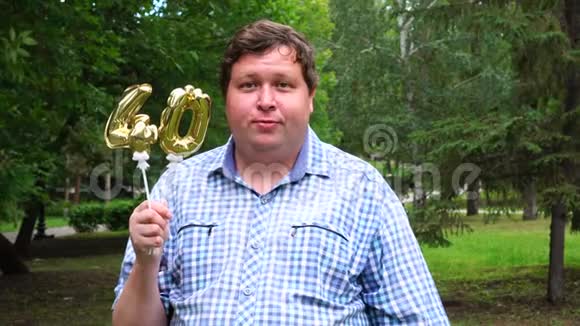 大个子拿着金色气球把40号放在户外40周年庆祝晚会视频的预览图
