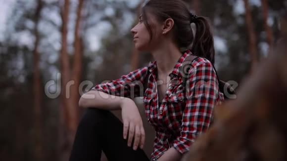 女人坐在森林的树干上放松地环顾四周视频的预览图