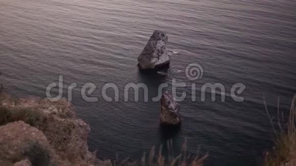 从岩石悬崖上看到海洋或海水空中观蓝水平静地与悬崖和岩石碰撞单独视频的预览图