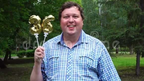 大个子拿着金色气球把36号放在户外36周年庆祝晚会视频的预览图