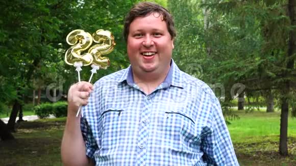 大个子拿着金色气球把22号放在户外22周年庆祝晚会视频的预览图