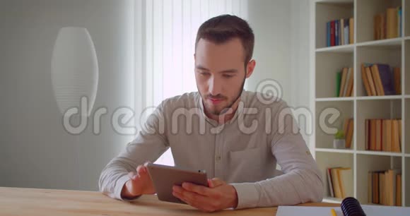 年轻英俊的白种人商人用平板电脑拍摄了一幅特写镜头他在室内开心地微笑着视频的预览图