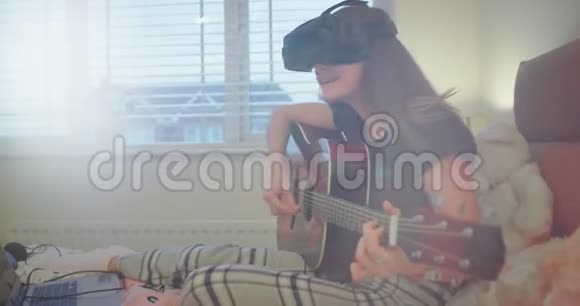 快乐的女孩弹吉他同时在卧室里使用虚拟现实非常热情地探索一种新的东西视频的预览图